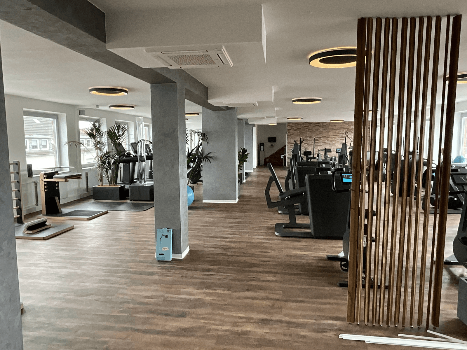 Fertig sanierter und modernisierter Fitness- und Gewerberaum mit Holzoptikboden und moderner Beleuchtung
