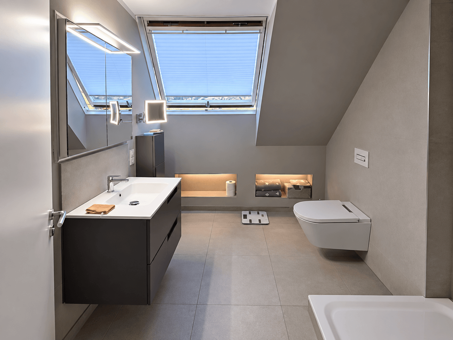 Modernes Designerbad nach der Sanierung mit anthrazitfarbenem Waschtisch, LED-Nischen und Dachfenster